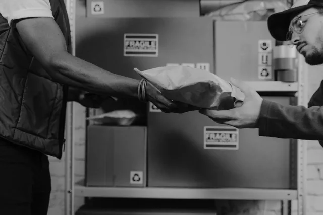 A delivery person hands a package to a client in an organized logistics center. Dropshipping returns and refunds
