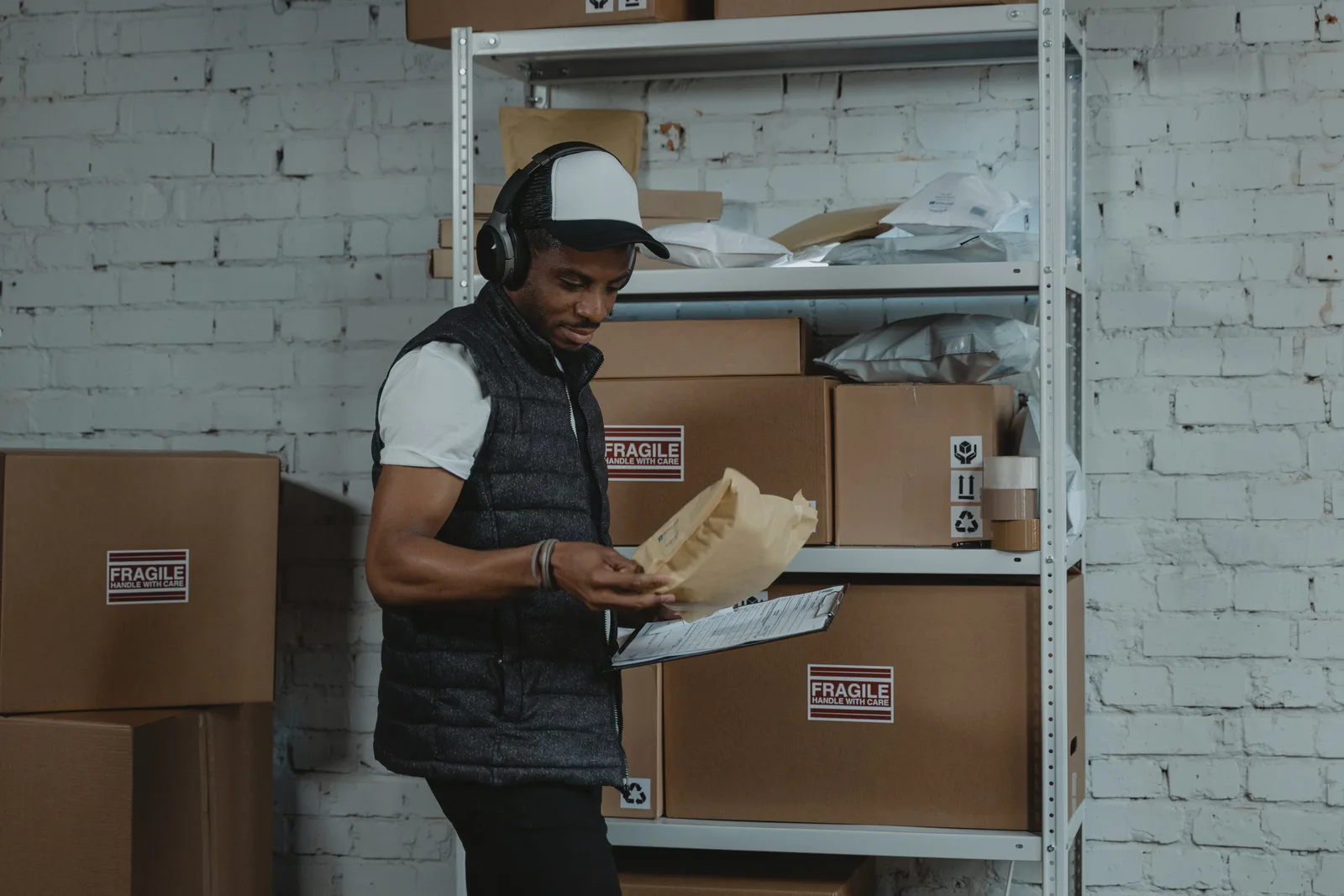 Warehouse worker sorting packages in an industrial environment with headphones on, focused and diligent.
