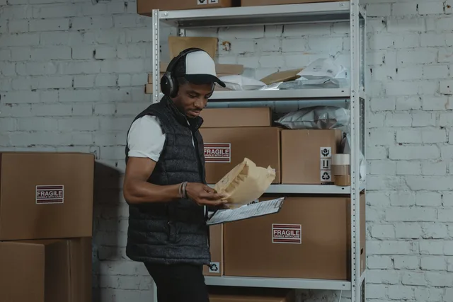 Warehouse worker sorting packages in an industrial environment with headphones on, focused and diligent. Finding dropshipping suppliers